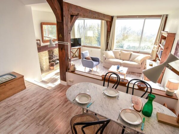 A spacious living area with a fireplace, a dining table set for four, and a cozy seating arrangement.