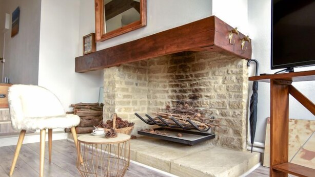 Ein gemütliches Wohnzimmer mit Kamin, Fernseher und bequemen Sesseln.
