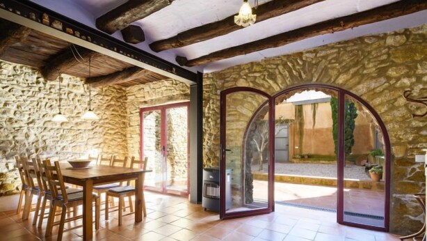 Un'area pranzo rustica con parete in pietra, tavolo e sedie in legno.