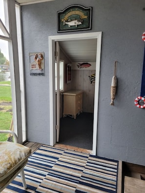 A room with a door leading to a bathroom, a wicker dresser, and a wall with a fish decoration. - Riverfront Getaway (Bay City)