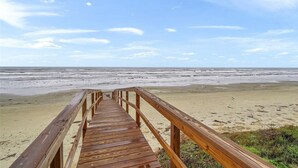 A wooden boardwalk leading to a beach with a clear sky. - Oceanfront modern 4BR home with stunning views (Galveston)