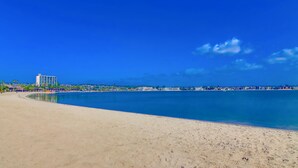 A beach with a clear blue sky, a sandy shore, and a distant view of buildings along the coastline. - San Diego Beach Home/ Mission Beach,Steps to Ocean&Bay, 2 Car Garage, AC/Heating (San Diego)