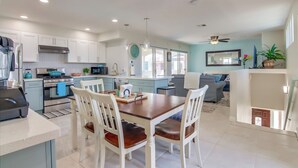 A modern kitchen with white cabinets, a dining table with chairs, and a living area with a sofa and a ceiling fan. - San Diego Beach Home/ Mission Beach,Steps to Ocean&Bay, 2 Car Garage, AC/Heating (San Diego)