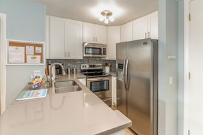 Eine moderne Küche mit Edelstahlgeräten, einer Mikrowelle, einem Backofen und einem Kühlschrank.