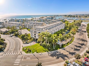 Ein mehrgeschossiges Hotel mit einem zentralen Innenhof, umgeben von einer Küstenstraße und einem Strand.