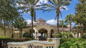 A sign for Windsor Hills Clubhouse with a Mediterranean architectural style, featuring arches and a fountain.