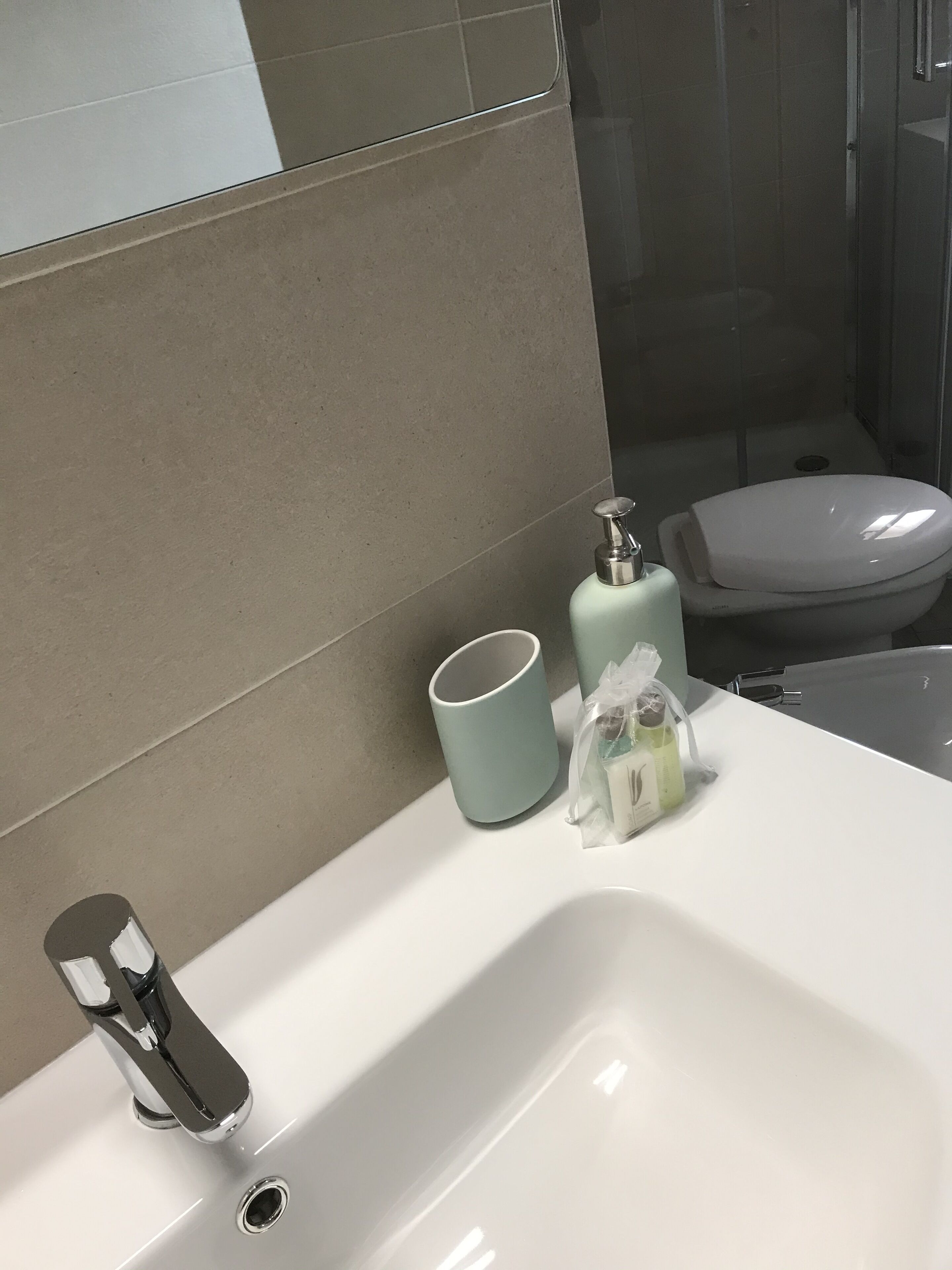 Une salle de bain avec un lavabo blanc, un miroir, des toilettes et un espace douche.
