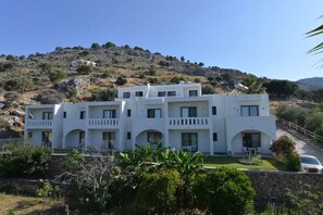 A white multi-story building with balconies, set against a hilly backdrop. - Golden View (Rhodes)
