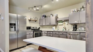 Una cocina moderna con electrodomésticos de acero inoxidable, un dispensador de agua integrado y una isla grande con asientos.
