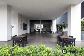 Un espace intérieur spacieux, avec deux tables et des chaises en bois, entouré de plantes en pot et doté d’un sol carrelé.