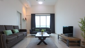 A modern living room with a sofa set, a coffee table, a TV, and a large window with curtains. - Ong Kim Wee Residence Melaka By I Housing (Malacca City)