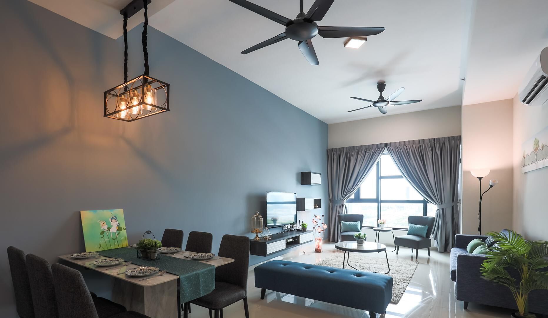 A modern living room with a dining area, two ceiling fans, a large window with curtains, and a flat-screen TV.