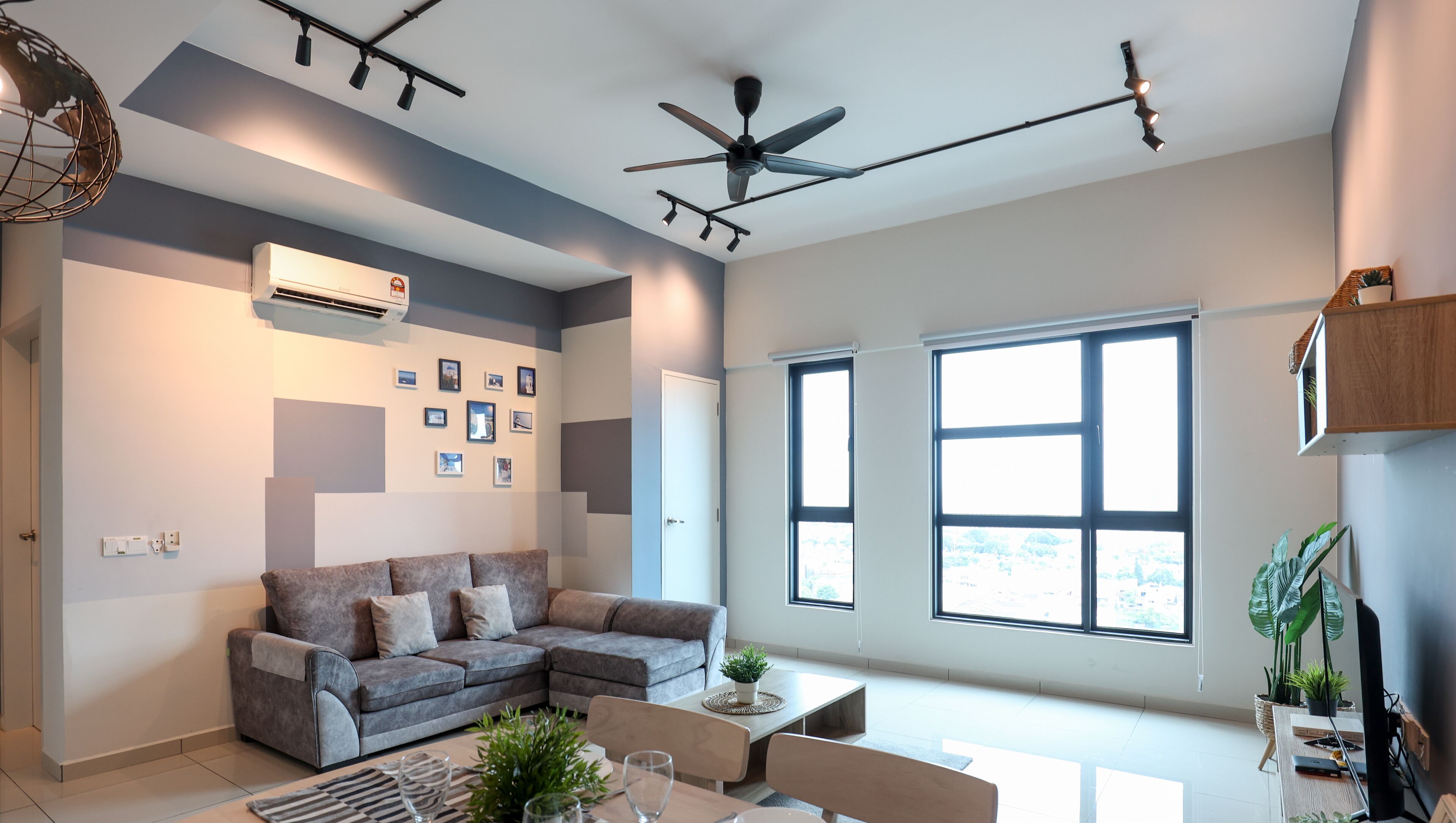 A modern living room with a sectional sofa, a dining table, and a ceiling fan.