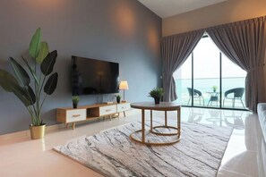 A modern hotel room with a large TV, a round table, a sofa, and a balcony with a view. - Ong Kim Wee Residence Melaka By I Housing (Malacca City)