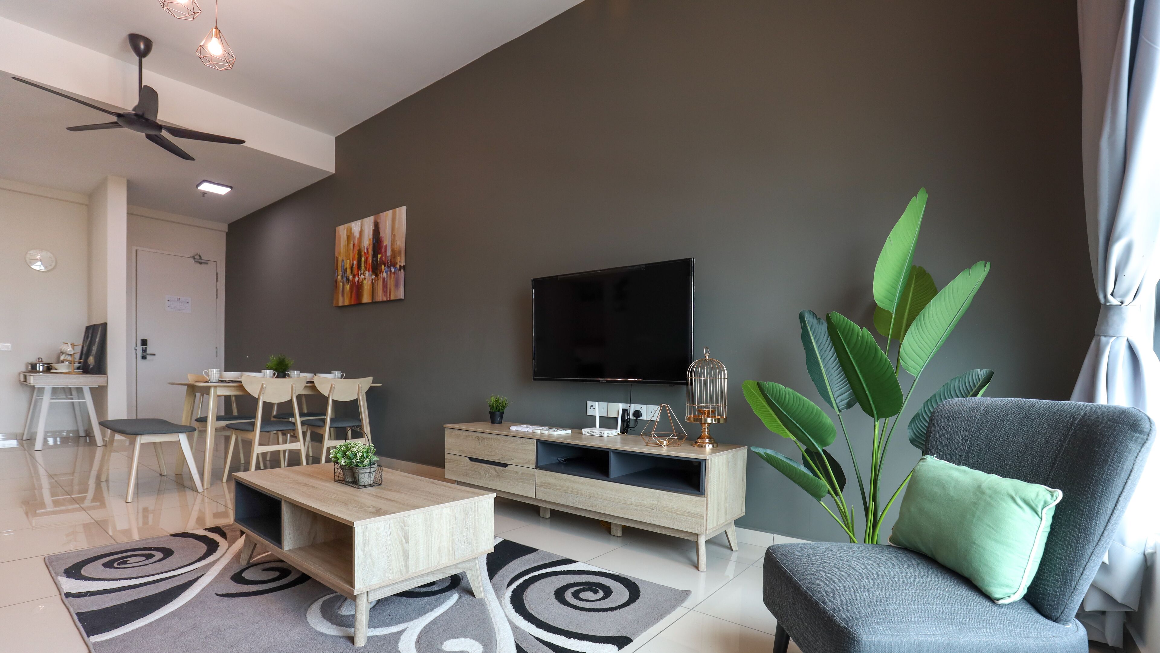 Una sala de estar moderna con televisor de pantalla plana, ventilador de techo y comedor con mesa y sillas.