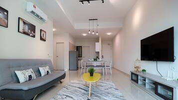 A modern living room with a grey sofa, a yellow coffee table, and a flat-screen TV mounted on the wall.