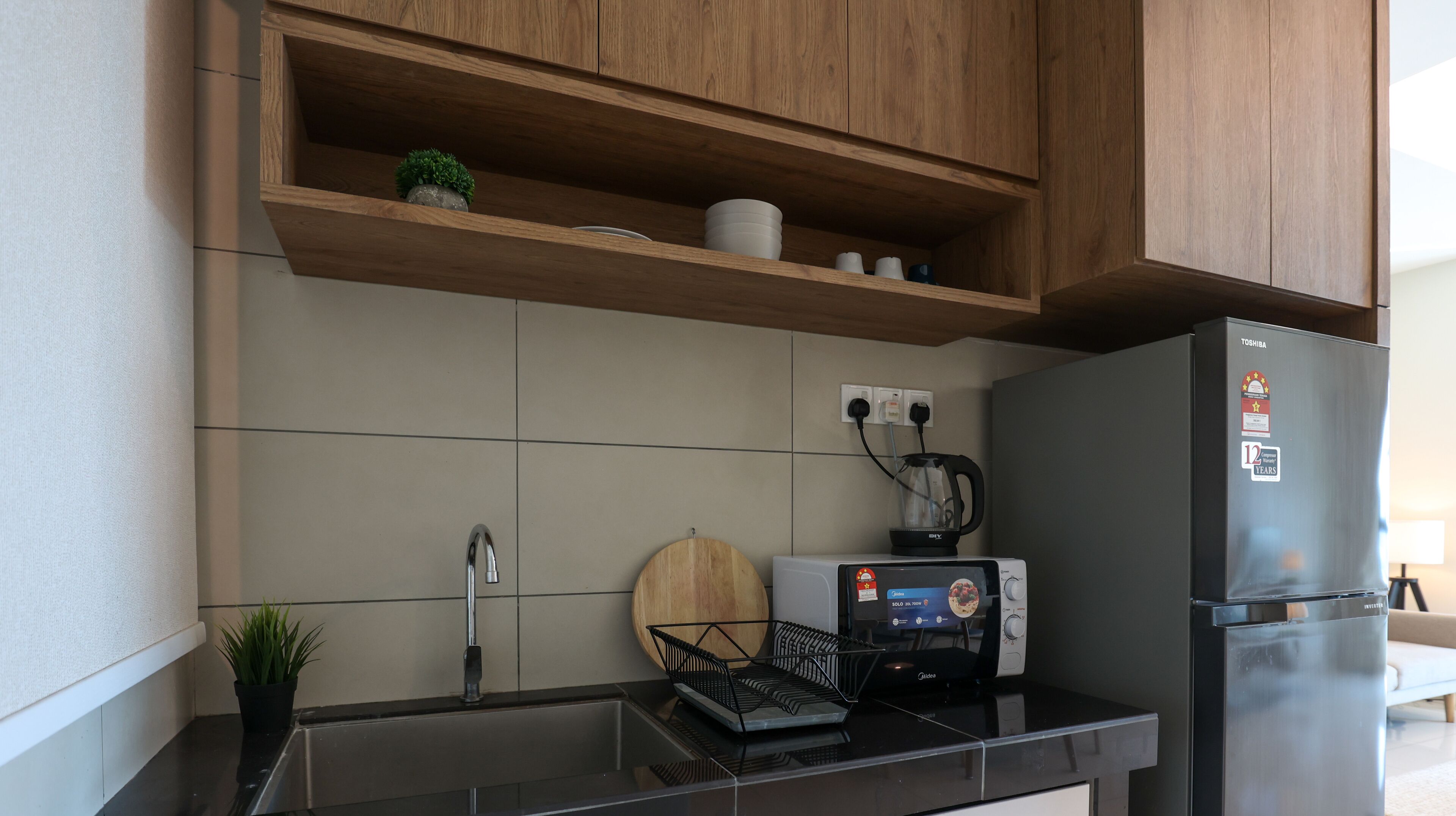Eine Küche mit Holzausstattung, einem schwarzen Kühlschrank, einer Kaffeemaschine und einem Toaster.