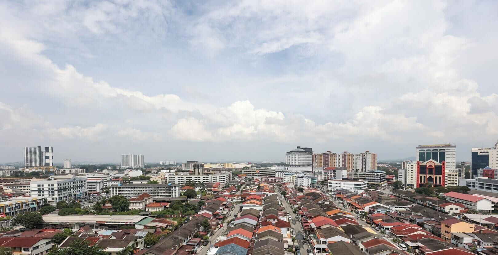 Un paysage urbain composé d’un mélange de bâtiments résidentiels et commerciaux, notamment des immeubles de grande hauteur et des maisons plus petites avec des toits rouges.