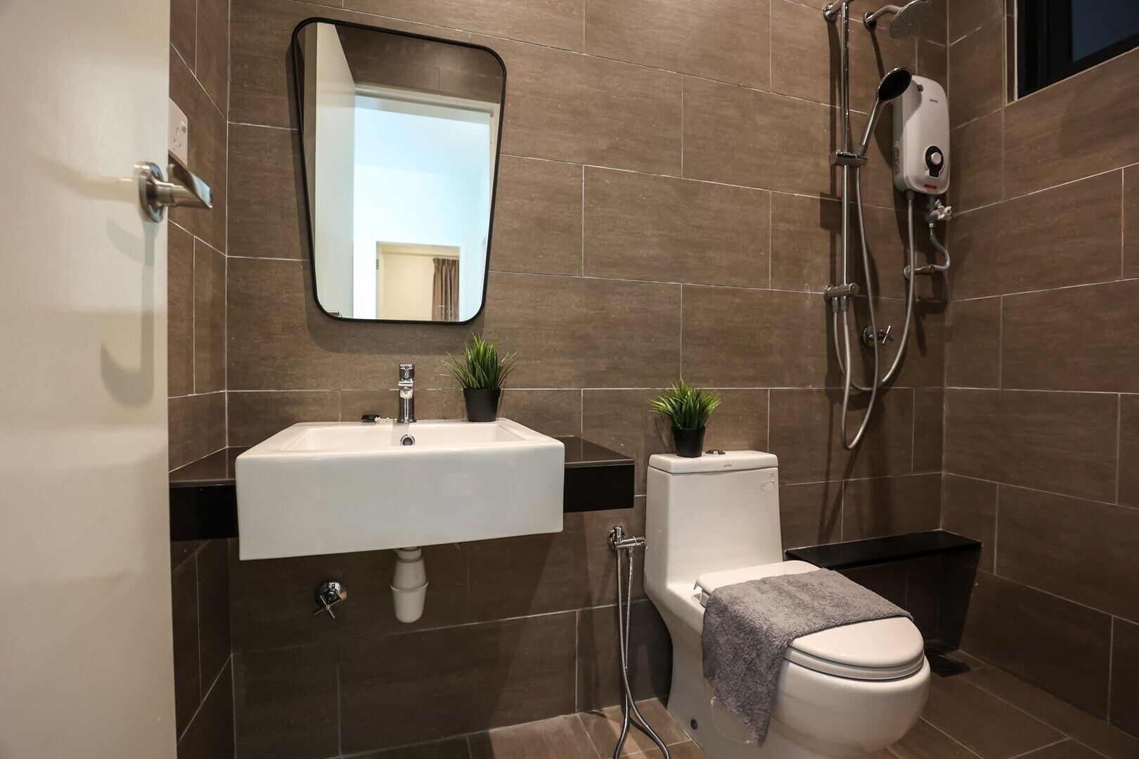 A modern bathroom with a white sink, a toilet, a shower, and a mirror.