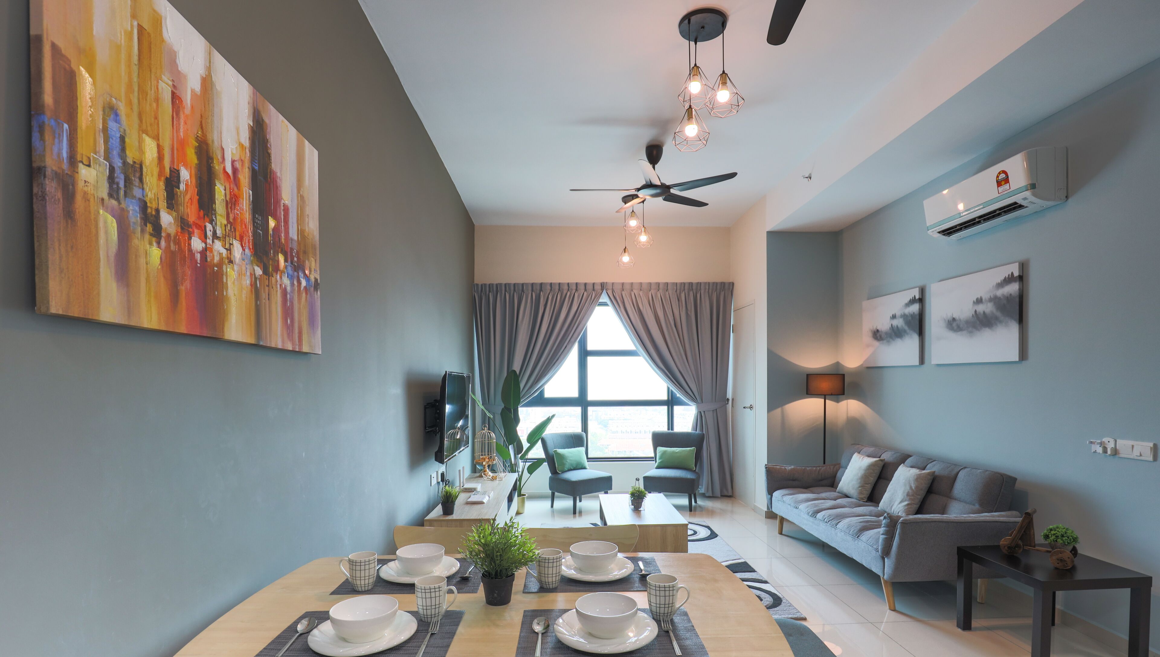 A modern living room with a dining area, grey walls, a ceiling fan, and artwork.