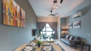 A modern living room with a dining area, grey walls, a ceiling fan, and artwork.