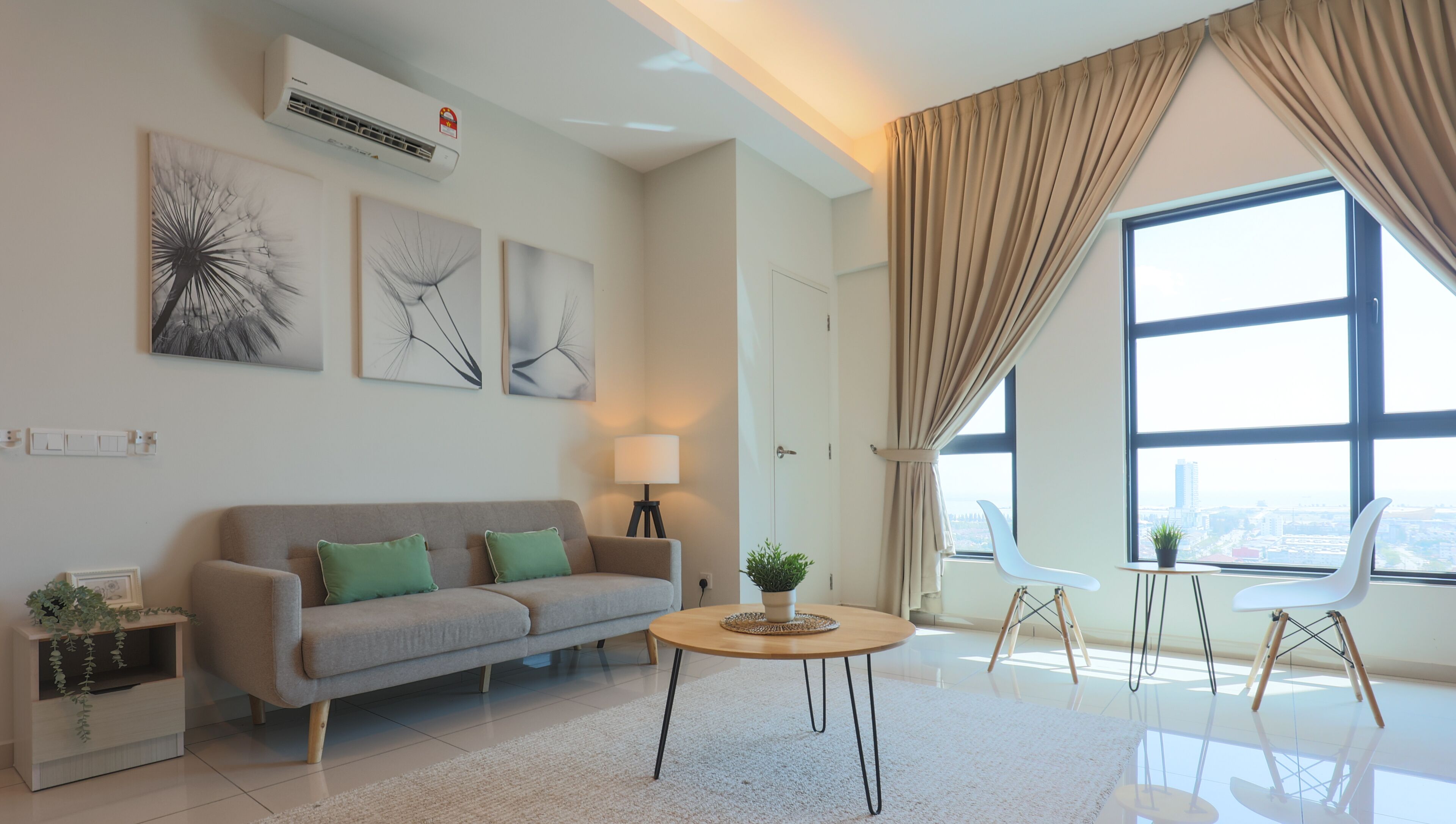 Uma sala de estar moderna com sofá, mesa de centro e vista da cidade através de amplas janelas.