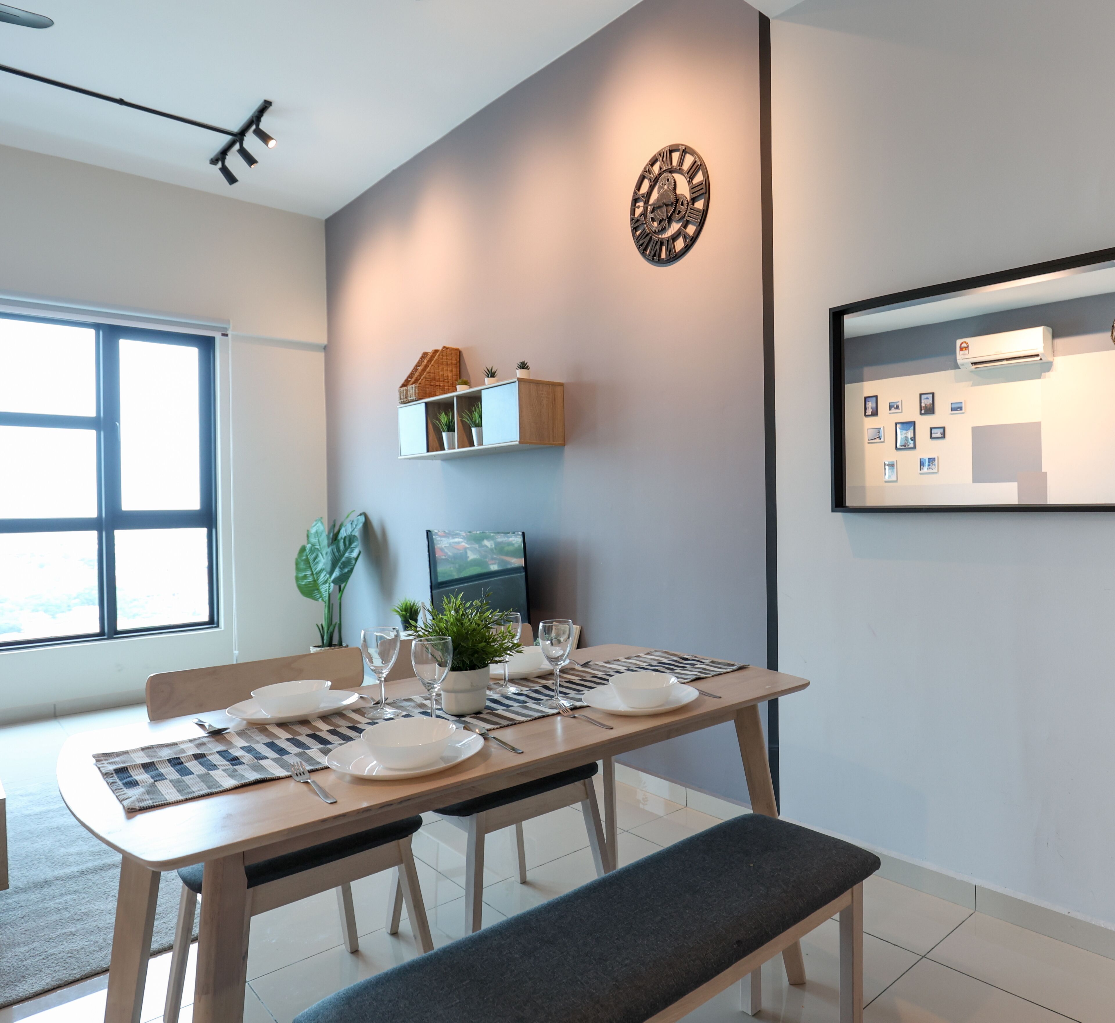 A modern dining area with a wooden table set for four, a bench, and a wall-mounted clock.
