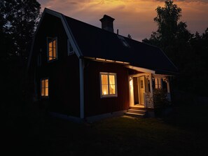 A house with a sloped roof, a chimney, and a lit entrance. - Grimsebo Vacation Home in an idyllic, secluded setting—pure nature! (Kalmar län)