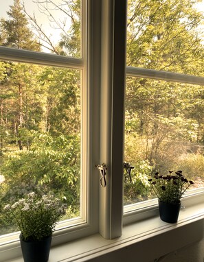 A window with two potted plants on the sill, overlooking a forested area. - Grimsebo Vacation Home in an idyllic, secluded setting—pure nature! (Kalmar län)