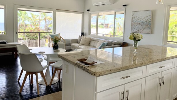Una cocina moderna con una isla grande, armarios blancos y vistas al exterior.
