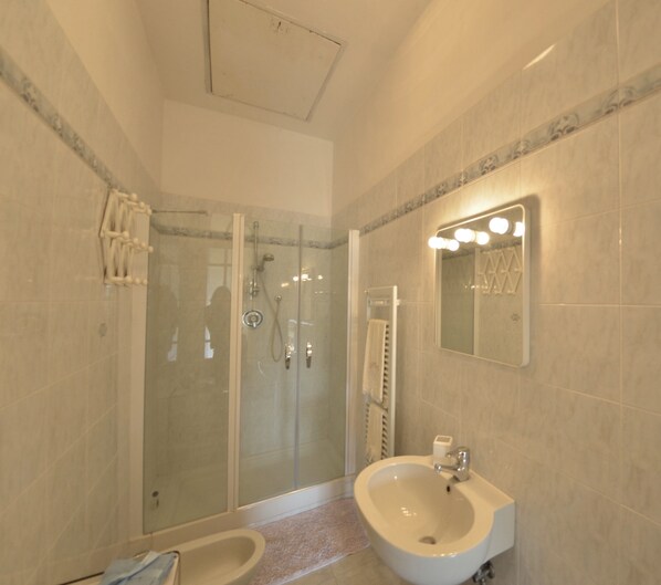 A modern bathroom with a glass-enclosed shower, a sink, and a mirror with lights.