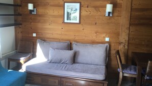 Ein Zimmer mit Holzwänden, einem Bett, zwei Wandlampen und einem gerahmten Bild an der Wand.
