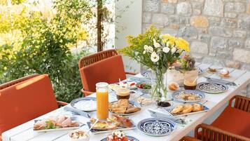 A table set for breakfast with plates of food, a glass of orange juice, and a vase of flowers.