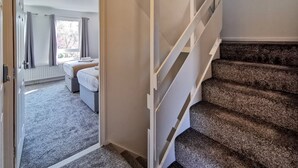 A staircase leading to a bedroom with a bed and a window.