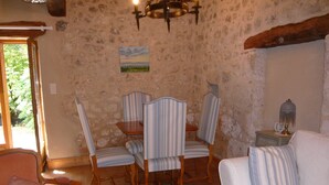 A dining area with striped chairs, a wooden table, and a chandelier. - luxury cottage for adult couples, peaceful, unobstructed views, large swimming pool (Boisse, France)