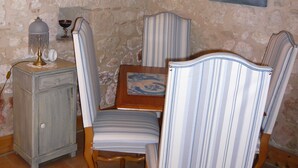 A dining area with a stone wall, a framed picture, a mirror, and striped upholstered chairs. - luxury cottage for adult couples, peaceful, unobstructed views, large swimming pool (Boisse, France)