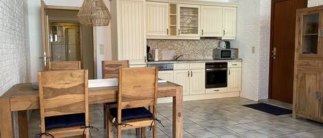A compact kitchen with wooden cabinets, a microwave, and a built-in oven.