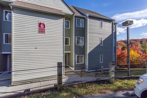 Un edificio residencial de varios pisos con fachada gris, una puerta de garaje visible y un acceso con valla.