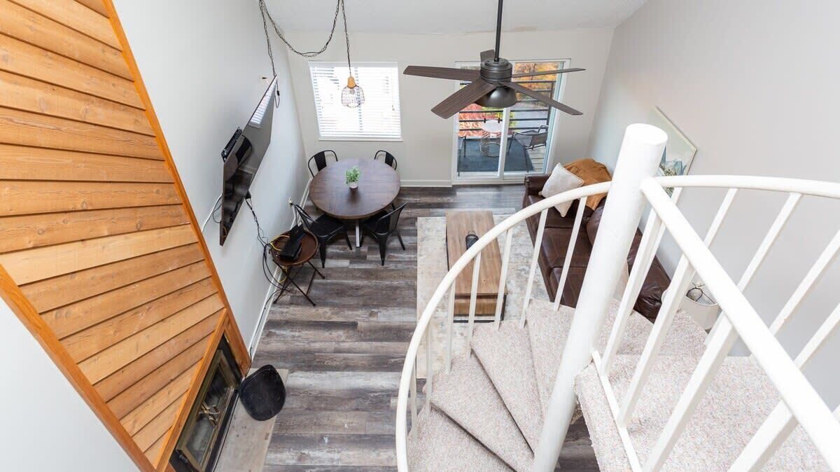 A staircase leading to a dining area with a table and chairs, a ceiling fan, and a view of the outdoors.