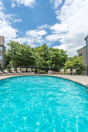 A swimming pool with clear blue water, surrounded by lounge chairs and a fence. - Sweeping Views Of GSMNP/Indoor Pool & Hot Tub (Gatlinburg)