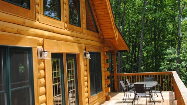 Eine Blockhütte mit einer Veranda, großen Fenstern und einem Essbereich.