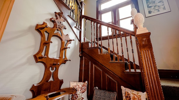 A wooden staircase with a decorative balustrade, a cushioned bench, and a floral-patterned pillow.