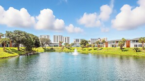 A lake with a fountain, surrounded by buildings and greenery. - Relax near Destin Beach. Destin’s best resort style condo! (Destin)