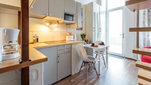 Eine moderne Küche mit grauen Schränken, einer Mikrowelle und einem Essbereich mit einem weißen Tisch und Stühlen.