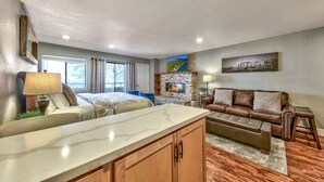 A modern living room with a fireplace, a large window, and a cozy seating area. - Lakeland Village #225 - Studio in Lodge, romantic remodel (South Lake Tahoe)