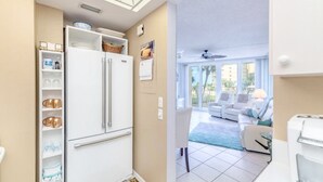Eine moderne Küche mit integriertem Kühlschrank, weißen Schränken und einer Essecke mit einer weißen Couch und einer Kaffeemaschine.