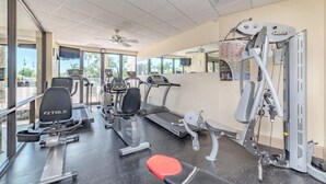 Ein Fitnessraum mit Laufbändern, einer Hantelbank und einem Kabelzuggerät.