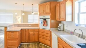 Une cuisine moderne avec des meubles en bois, un four encastré, un évier et des luminaires suspendus.
