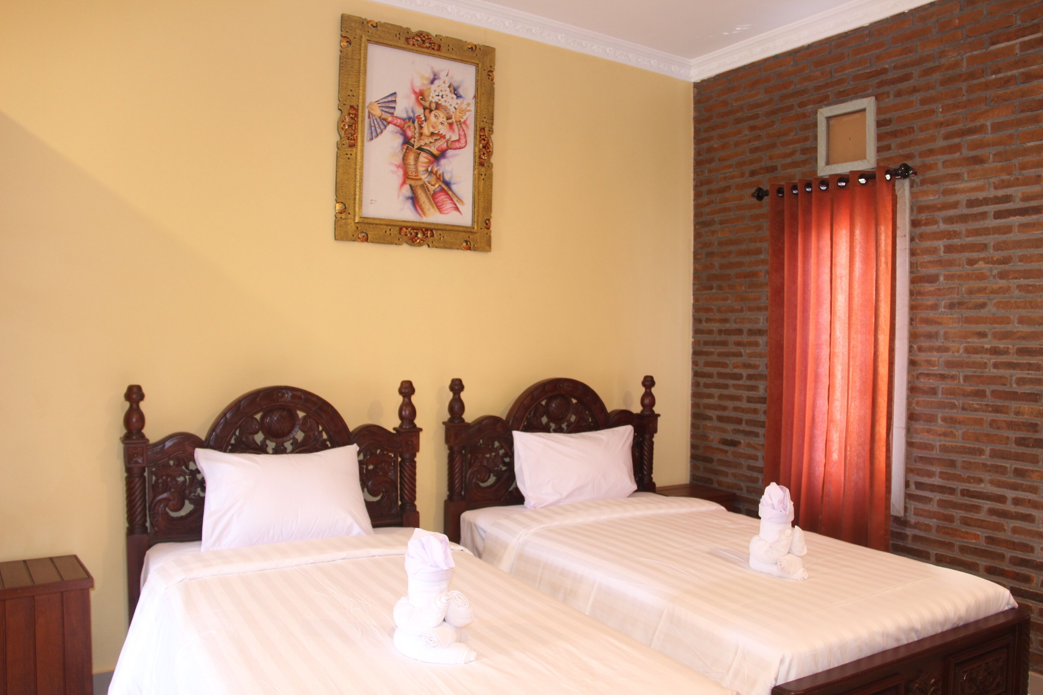 Quarto de hotel com duas camas de madeira, uma parede de tijolo e um quadro pendurado na parede.