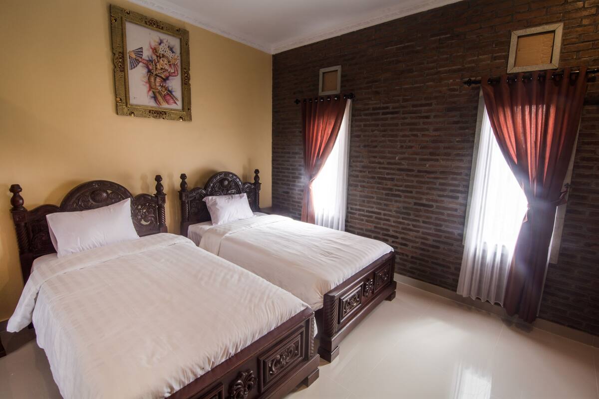 A room with two wooden beds, a brick wall, and a framed picture on the wall.